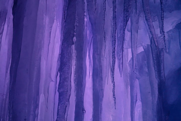 CLOSE UP: Long glassy ice stalactites hang from the ceiling of an icy cavern.