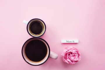 Two cups of coffee, a delicate flower and numbers. Greeting card for Women's Day March 8th. Trendy pink background. March 8 and the concept of "Women's Day".