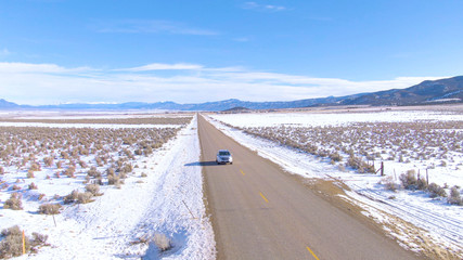DRONE: Tourists in SUV explore the snowy flatlands of Utah on a sunny winter day