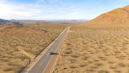 DRONE: Tourists in SUV explore the arid flatlands of Nevada on a sunny day.