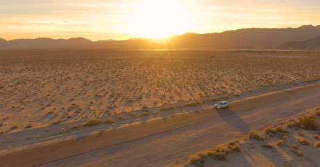 LENS FLARE: Flying above a SUV cruising across the Mojave desert at sunset.