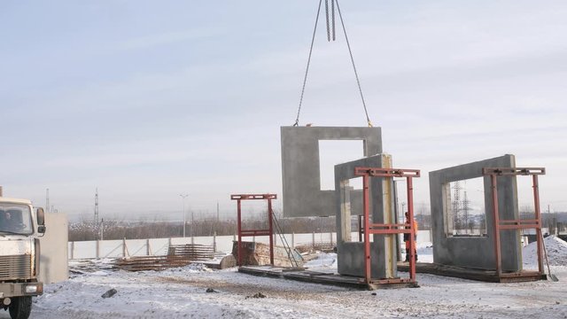 special mechanism lifts hooked wall panel for building monolithic house against snowy field in cold winter weather