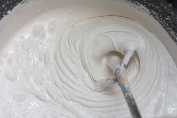 Building mixture in the process of preparation. A worker mixes the plaster in a bucket to level and putty the walls of the apartment with an electric drill, close-up.