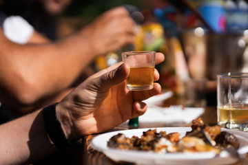 Guests holding glass with whiskey and toasting at wedding reception in restaurant, cropped view. People holding drinks and cheering, listening to toast. Luxury banquet, christmas feast. Rest concept