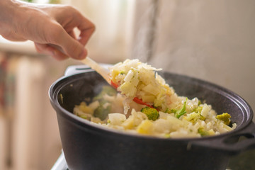 a big pilaf pan bowl with mix of vegetables , cooking on the kitchen