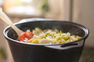 a big pilaf pan bowl with mix of vegetables , cooking on the kitchen