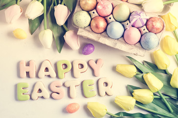 Golden Easter Eggs in box with yellow tulips on stone marble background. Easter toned background