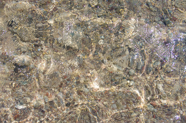 Background of the seabed. Sea stones, clear water and beautiful glare. Seaside