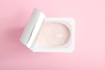 Tasty yogurt in a plastic glass on a colored table top view. Place to insert text. Useful snack.