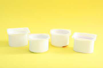 Tasty yogurt in a plastic glass on a colored table. Place to insert text. Useful snack.