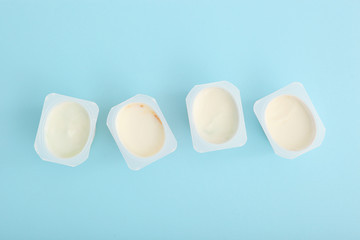 Tasty yogurt in a plastic glass on a colored table top view. Place to insert text. Useful snack.