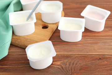 Tasty yogurt in a plastic glass on a colored table. Place to insert text. Useful snack.