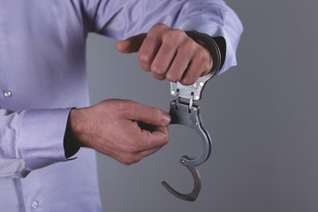 man hand handcuffs in back on the dark background