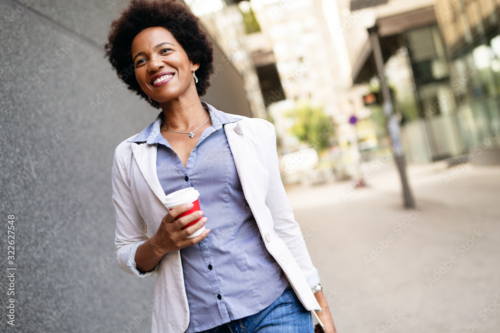 Wall mural smiling happy business woman, lawyer walking with coffee in city