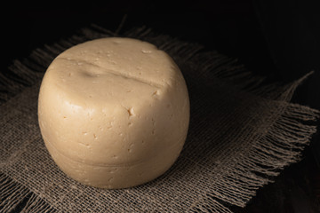 cheese head lies on a rough burlap lying on a rusty surface.