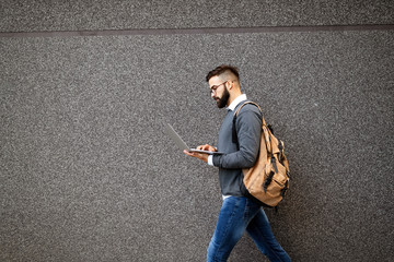 Businessman walking in street holding his laptop, working outdoor