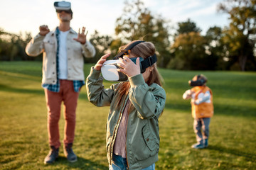 Innovation. Family playing in virtual reality glasses outdoors