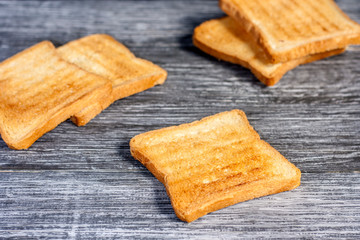 Several slices of toasted bread toasts on a wooden dark background