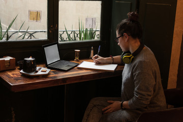 Young student is studying in a coffee shop with her laptop