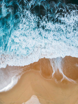 Aerial drone shot of deep blue waves crashing on sandy beach Mexico