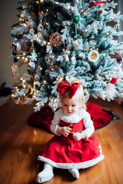 Young girl sitting in front of Christmas tree