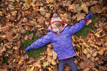 Little girl playing in the leaves in a park in Vienna, Austria.