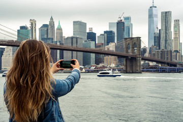 attractive woman using her smartphone with the New York skyline in the background