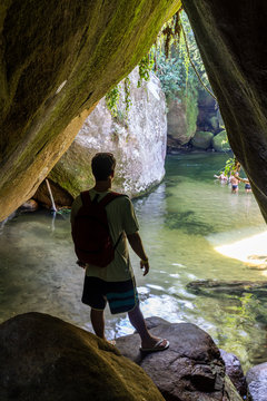 Man inside cave looking into beautiful green river in Serra dos &rdquo;rg&bdquo;os