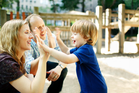 Son giving parents high fives at playground