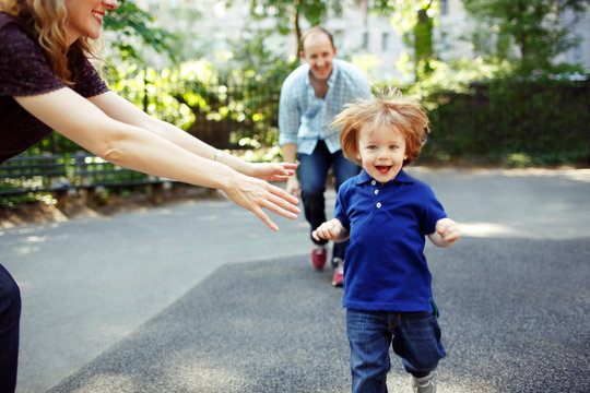 Boy running towards camera as parents playfully chase him