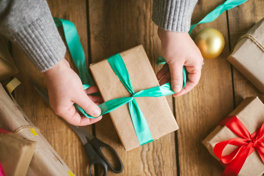 Woman wrapping christmas gifts on wooden background