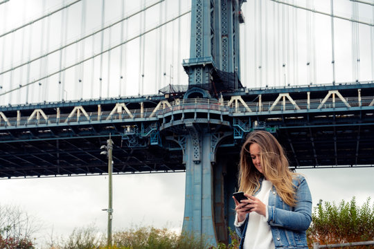 Attractive woman using her smartphone on the Manhattan Bridge