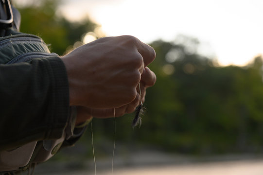 A man tying on an artificial fly called a wooly bugger