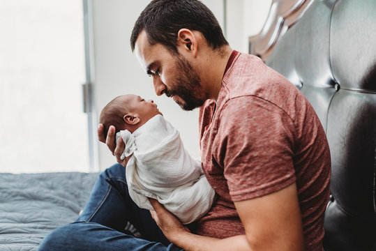 Mid-30?s dad with beard admiring newborn wrapped in white blanket