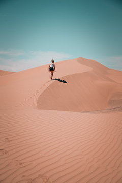 Young Woman Hiking On A Desert Dune Leaving Footmarks In The Sand
