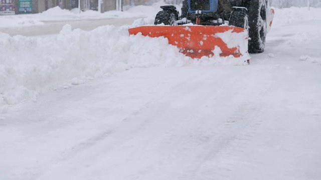 Snow plow tractor cleans road from snow in the winter