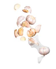 Cloves of garlic fly out of a mesh bag, isolated on white background