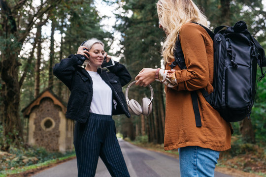 Women listening music with headphone in a countryside forest road