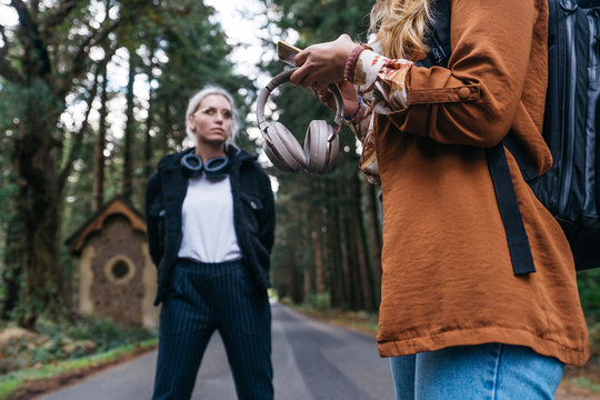Woman holding headphone and smartphone on a road in the countryside