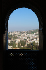 View to Granada city through the openwork arched window of Generalife palace, Alhambra, Granada, Spain