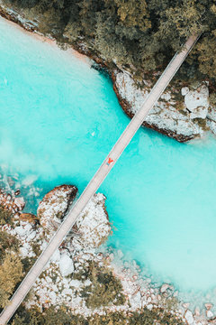 Female laying on rope suspension bridge over teal white water river