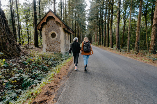 Two girls walking down a road and listening to music