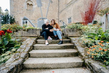 Young women using their smartphone sitted on stairs in a french town