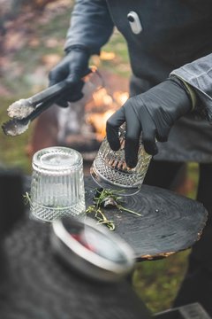 Someone smokes a glass with a lump of charcoal to make a smoky cocktai