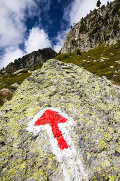 An arrow pointer on the rock in Val D' Arpette in the Swiss alps on the Tour du Mont Blanc path.