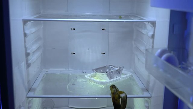Open empty fridge. Nothing to eat or strict dieting. Night hunger. Hangover. Bachelor's fridge, view from behind. Dirty fridge. Time for shop.