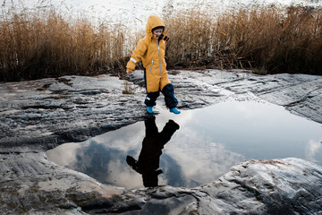 boy and his reflection jumping over water on an island in Sweden