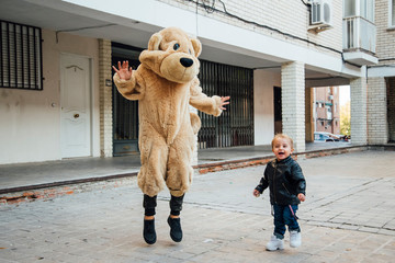A little boy playing with a giant teddy bear.