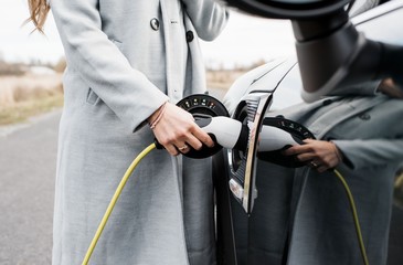 view of woman's hand plugging in charging lead to her electric car