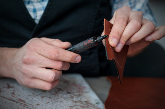 Close-up of craftsman applying black paint on leather edge while processing leather - Powered by Adobe